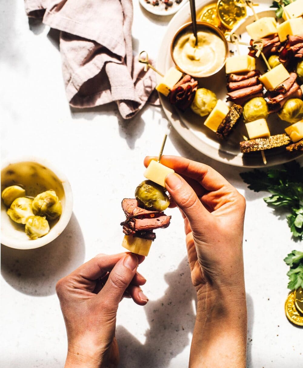 putting meat and cheese on a wooden skewer