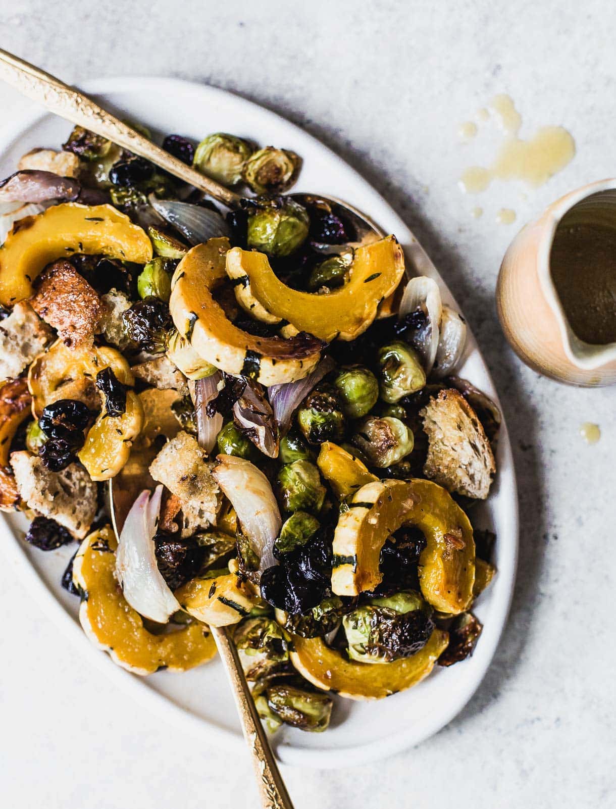 Vegan Stuffing on a white platter. with squash, brussels sprouts, and dried tart cherries