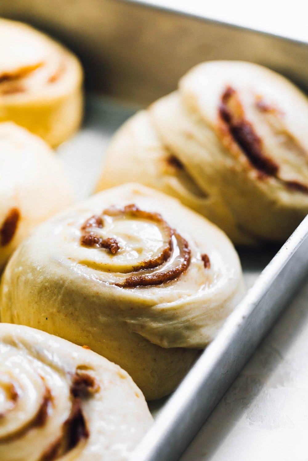 cinnamon roll dough rising in an aluminum pan