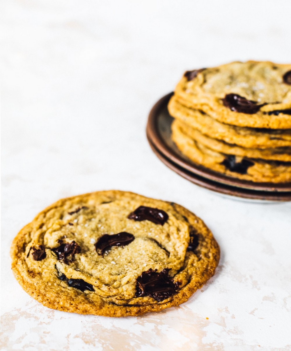 giant chocolate chip cookies, with 4 stacked on a plate in the backround