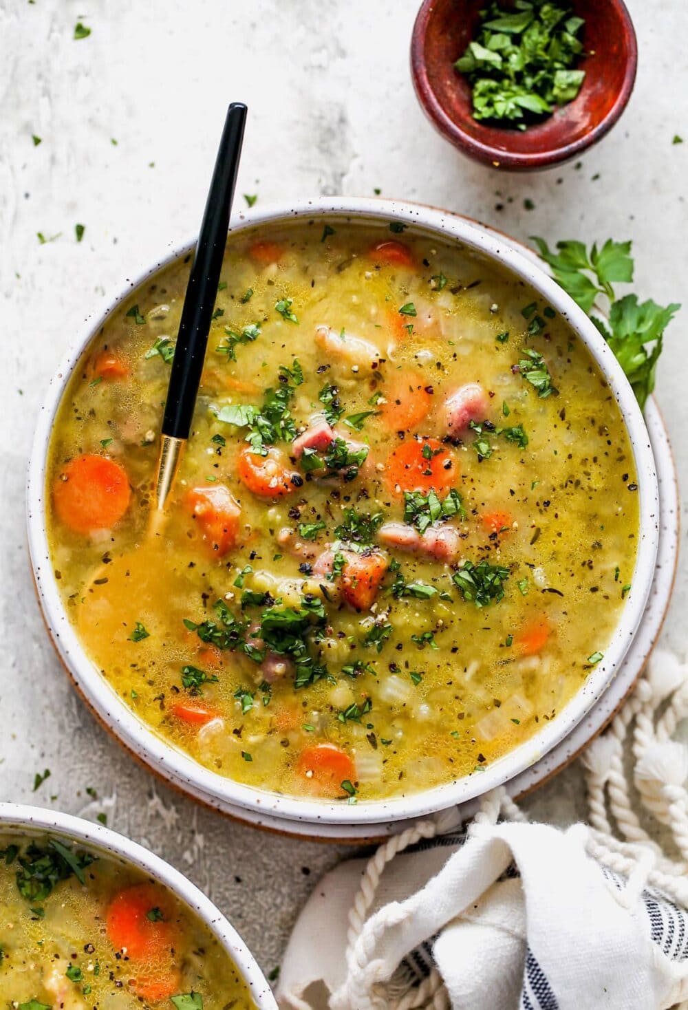 split pea soup in a white bowl, with spoon sticking out it.