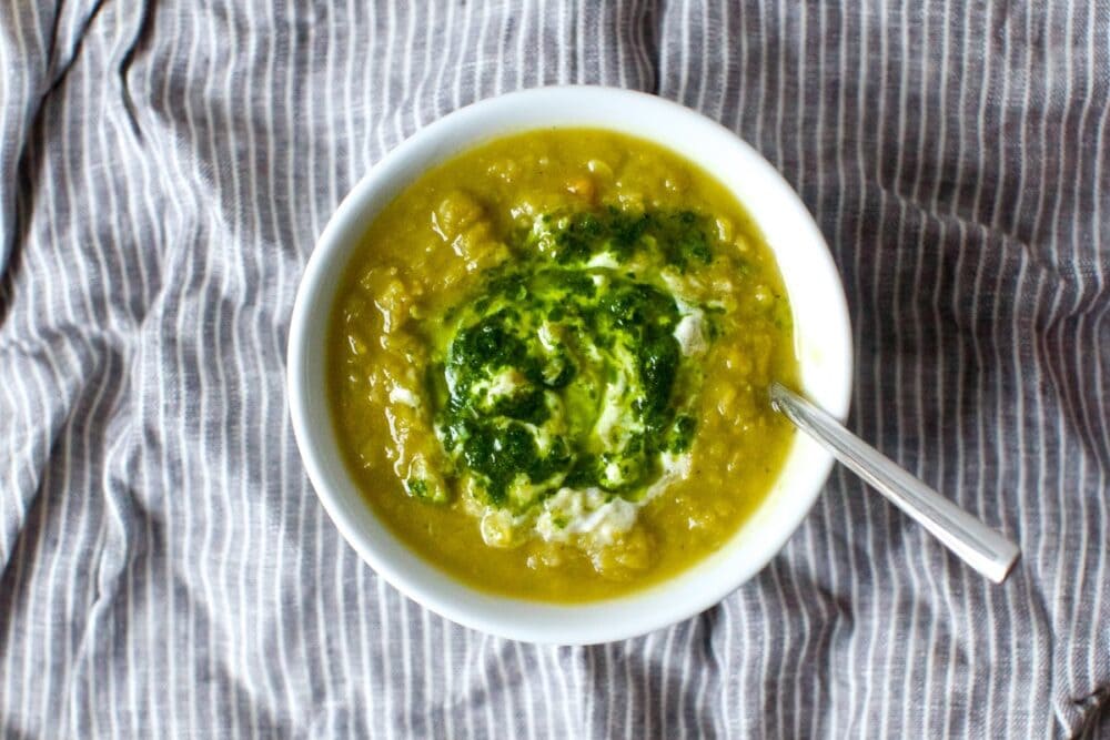vegetarian split pea soup in white bowl with pesto on top
