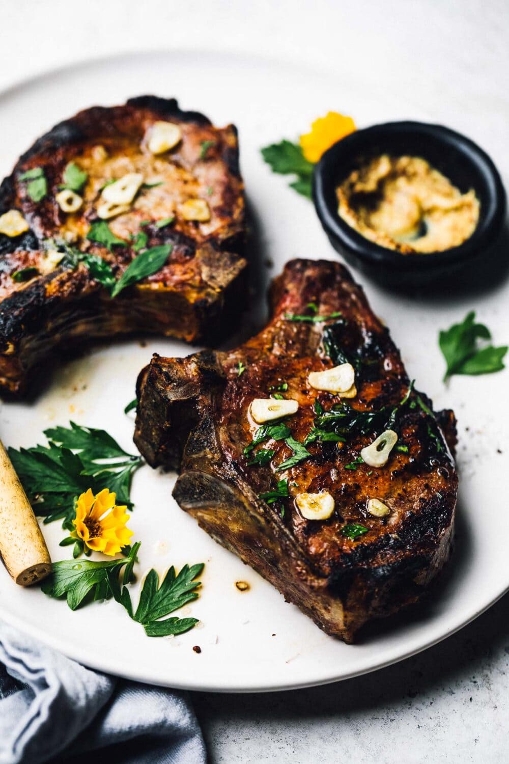 grilled bone in pork chops with garlic butter on a white plate