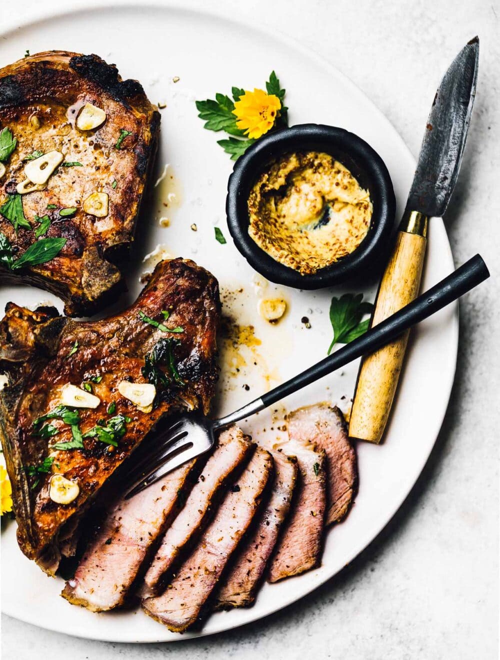 grilled bone in pork chops, sliced on a white plate