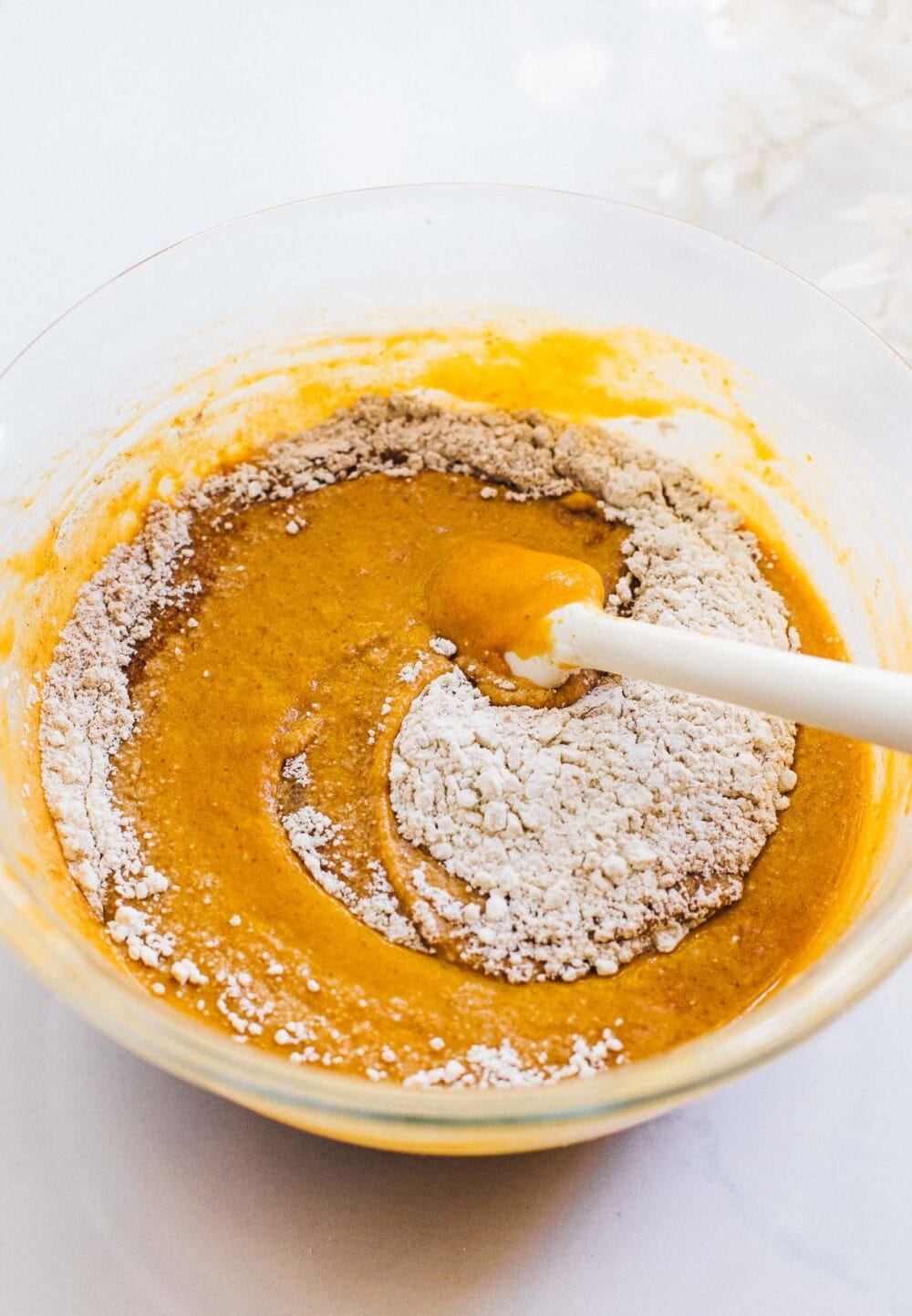 mixing sourdough discard pumpkin bread, ingredients in glass bowl.