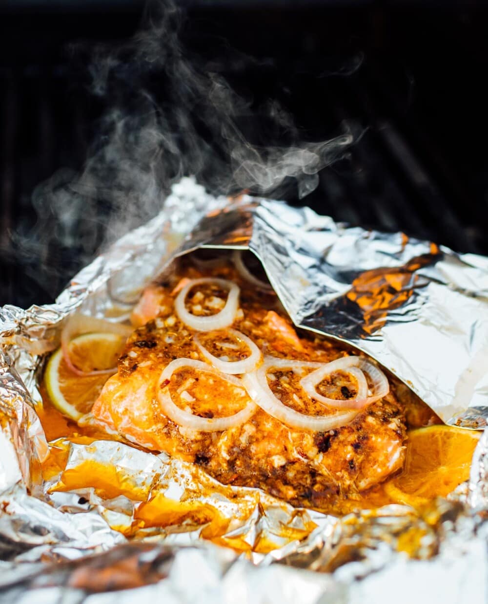 salmon in foil on the grill with smoke coming out