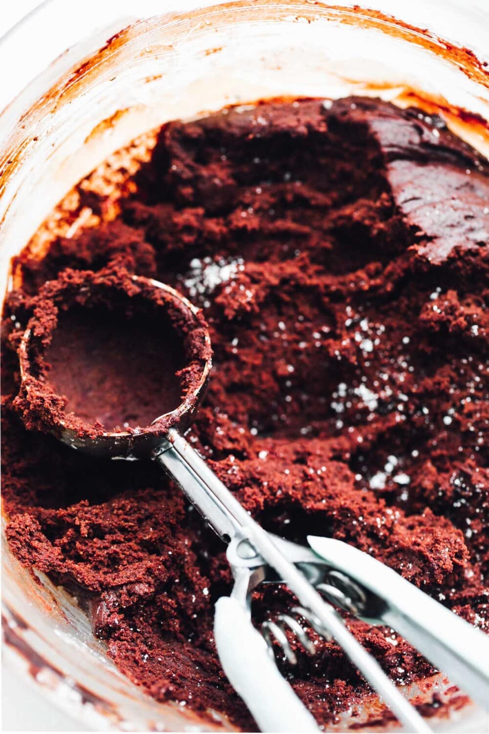 red velvet cookie dough in bowl with a cookie scoop