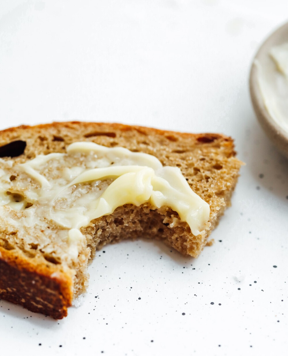 einkorn sourdough bread with butter on it, and a bite taken out