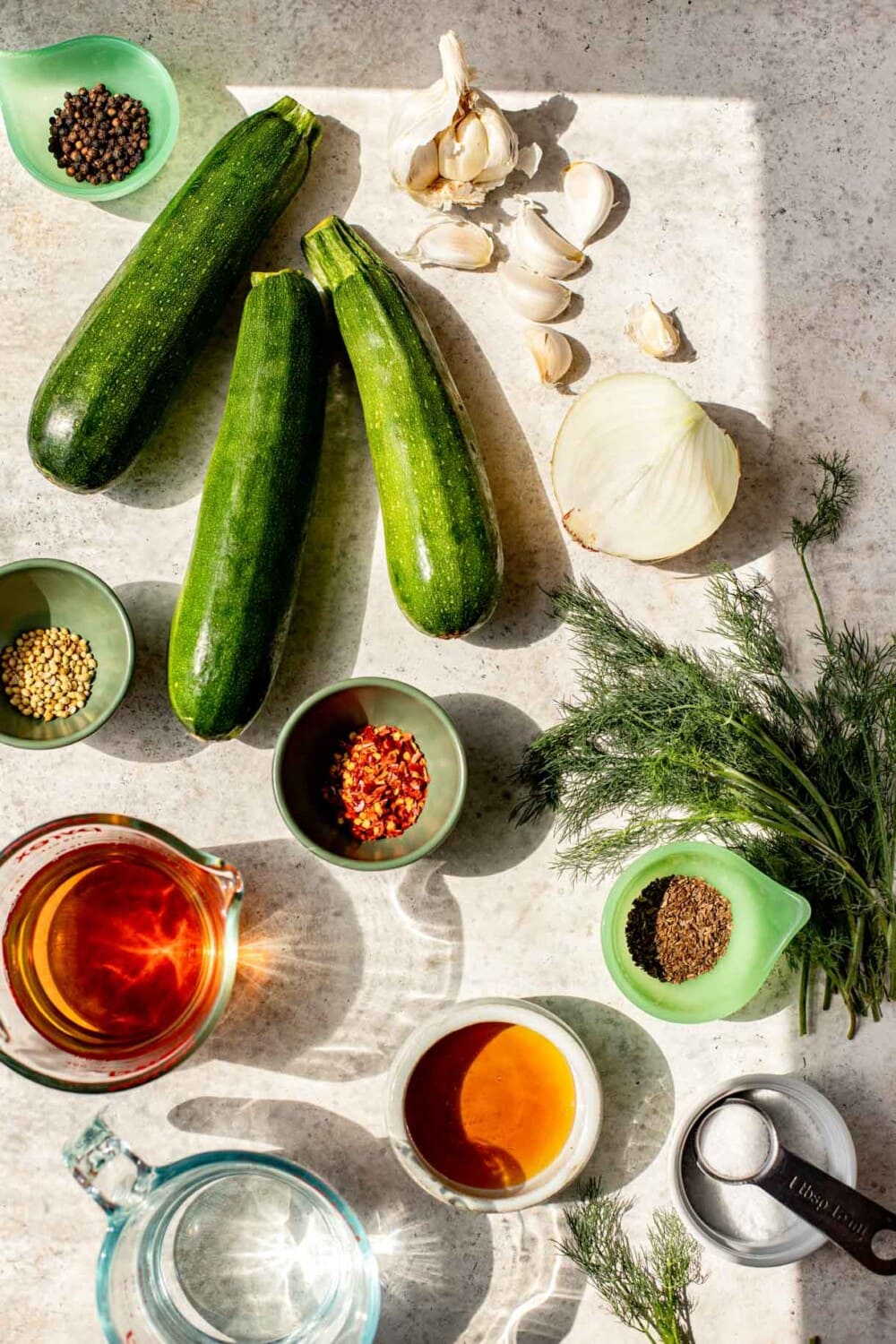 ingredients for pickled zucchini on a white surface