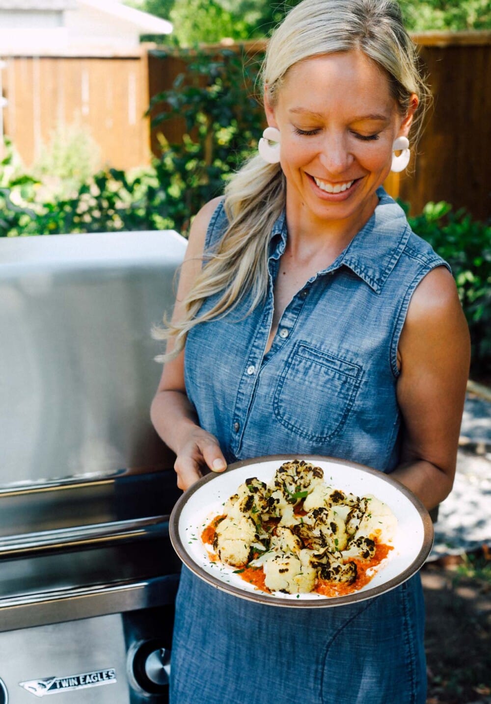 woman holding plate of grilled cauliflower