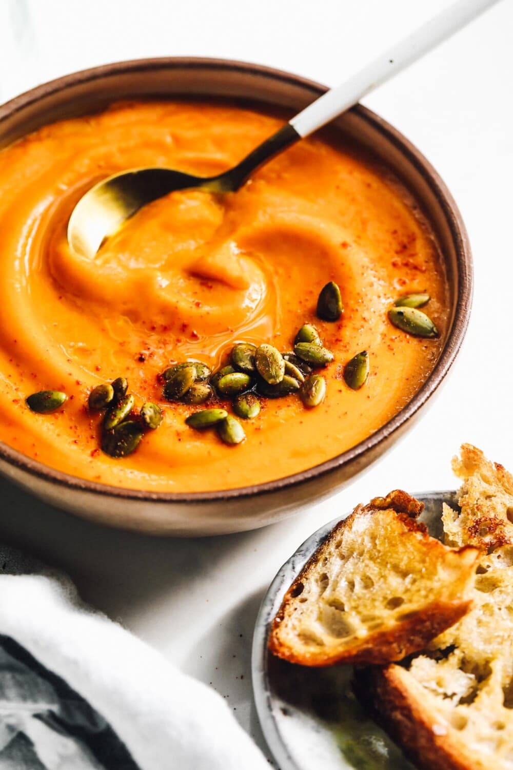 buttercup squash soup in a bowl with a plate of toast next to it. 