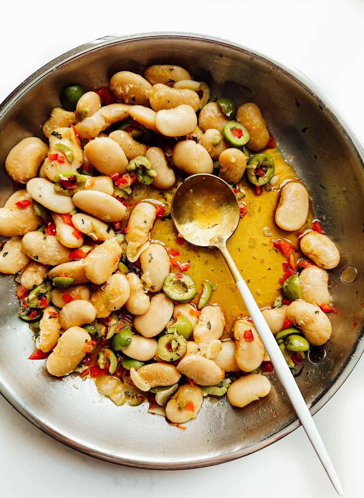 marinated gigante beans in a stainless steel skillet