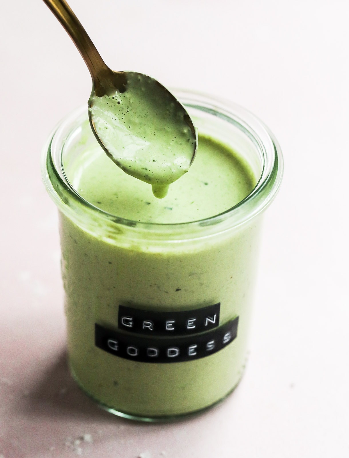 green goddess dressing in clear jar with gold spoon