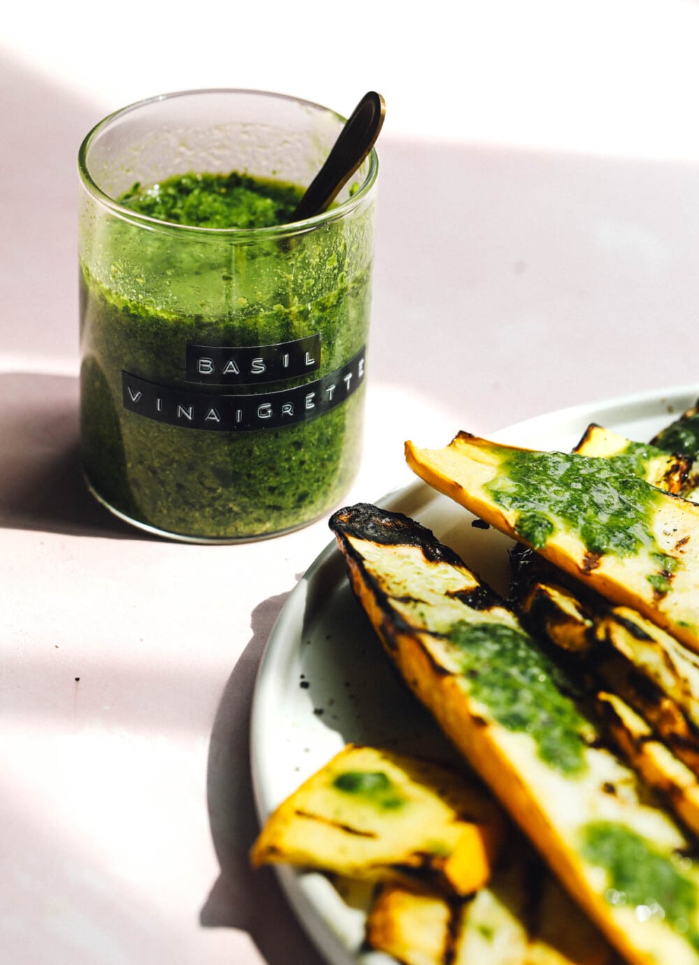 basil vinaigrette in glass jar with label sitting next to summer squash