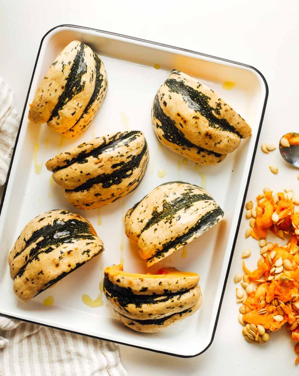 sweet dumpling squash cut into wedges on a white enamel tray