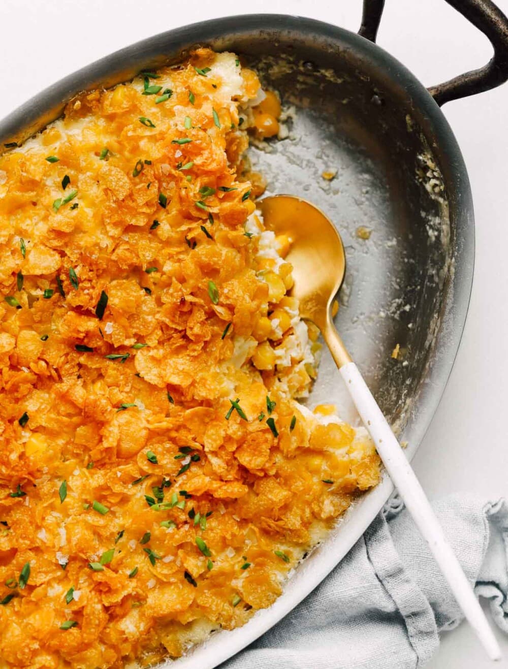 cream cheese baked corn in a casserole dish with gold spoon