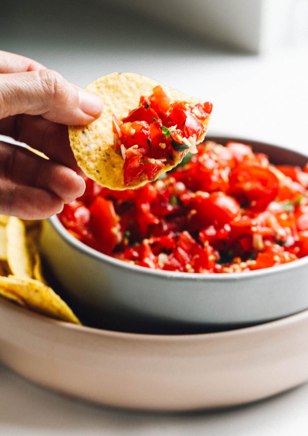woman holding chip with cherry tomato salsa