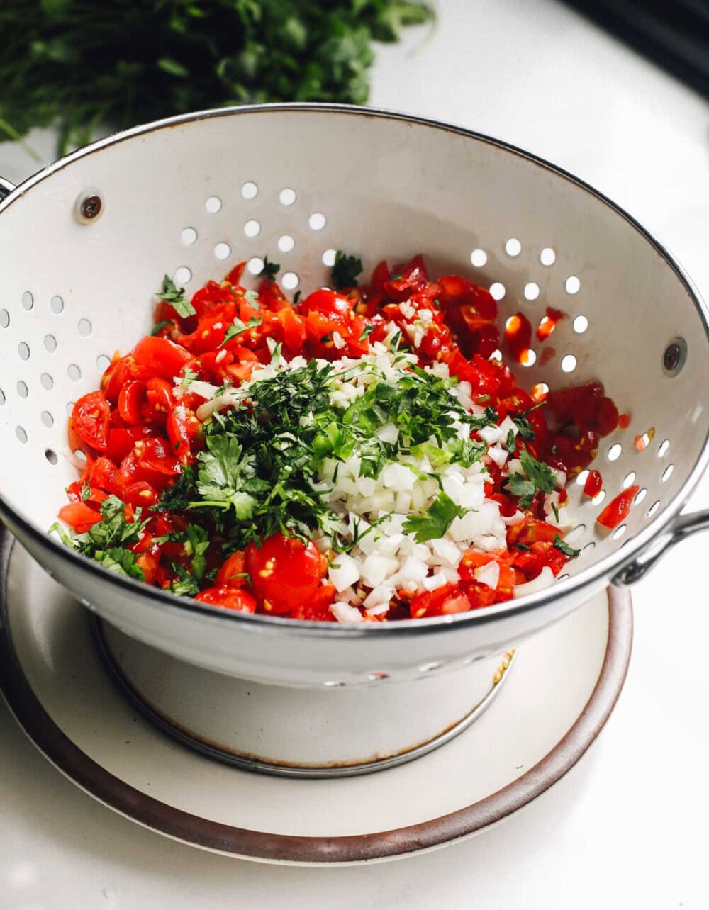 chopped salsa ingredients in a colander