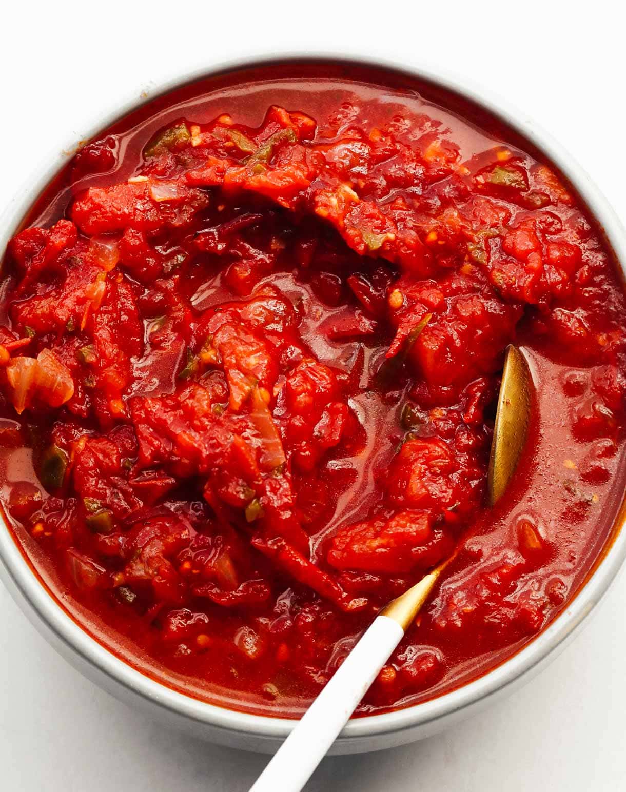 stewed tomatoes in bowl with gold spoon