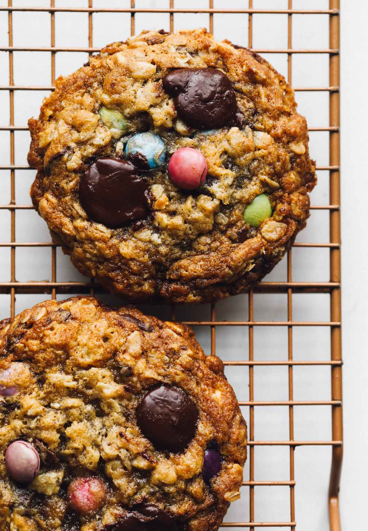 Two sourdough monster cookies on a wire cooling rack.