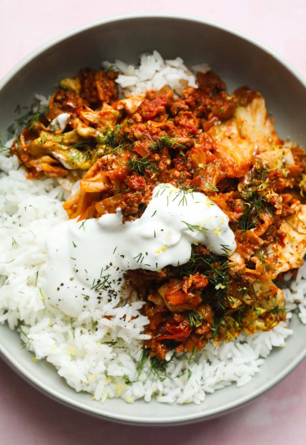 close up of cabbage roll in a bowl with sour cream dollop