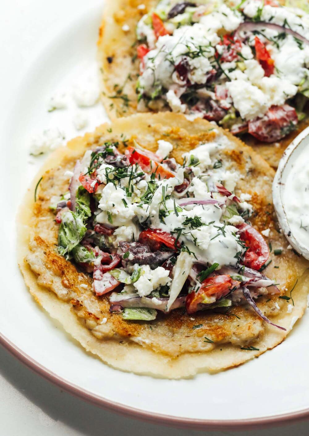 Two greek ground chicken smash tacos on a plate.
