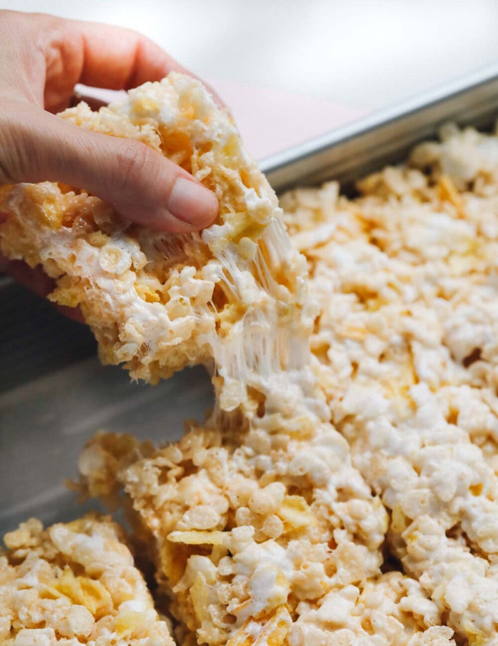 pulling a rice krispie treat out of a metal pan