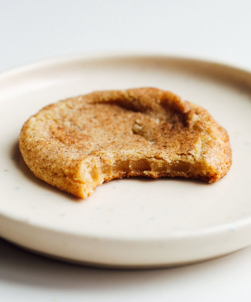 brown butter snickerdoodle cookie on a white plate with bite taken out of it